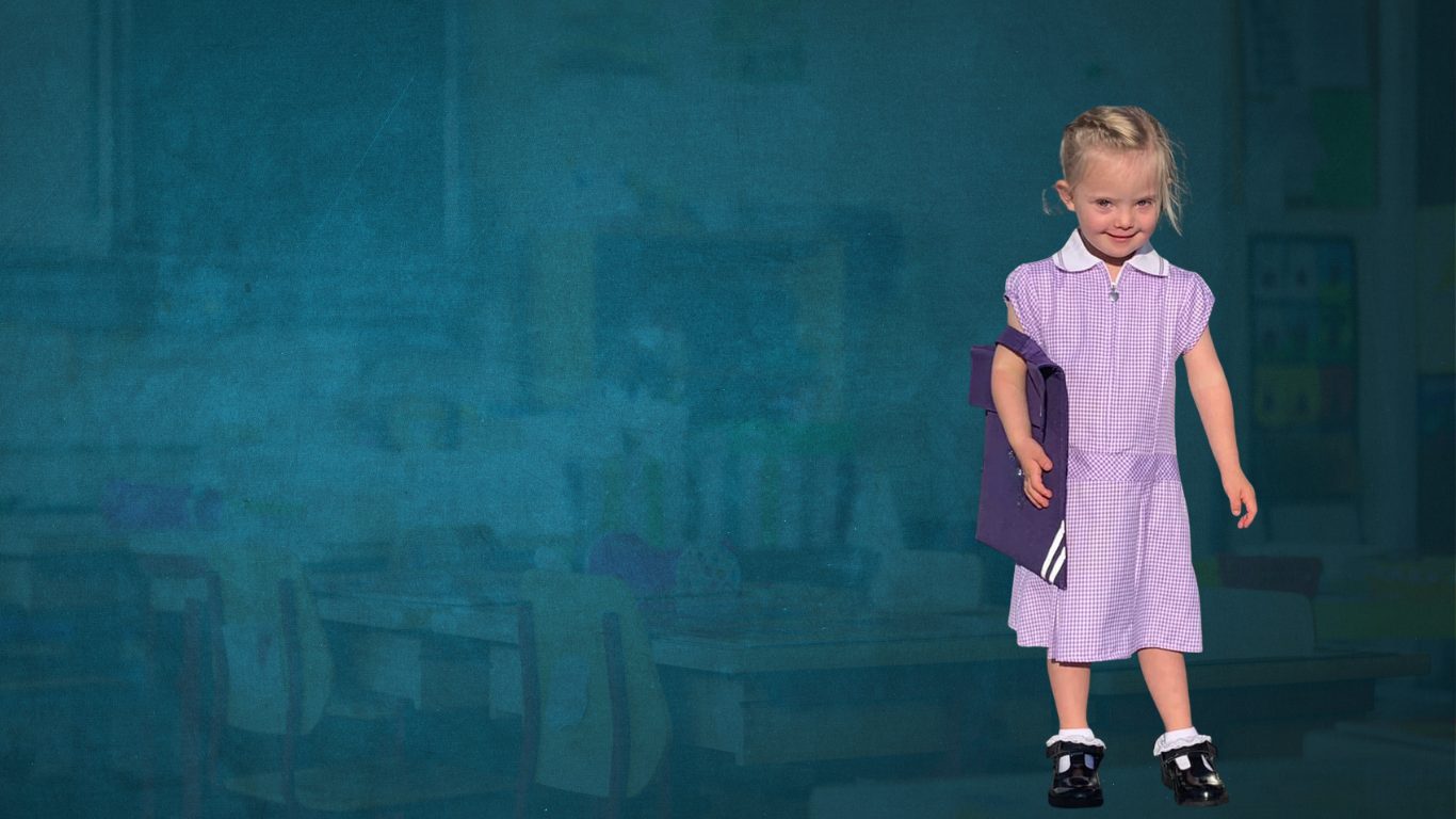 Child in a primary school outfit holding her bag under her arm and smiling for a photo