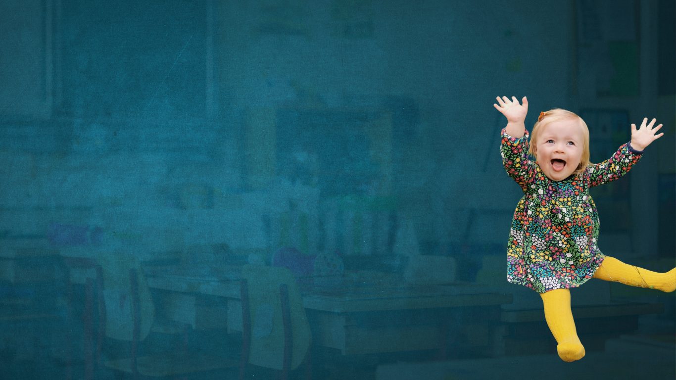 Toddler sat on floor with legs spread out and hands in the air, her mouth is open wide in a happy exclamation