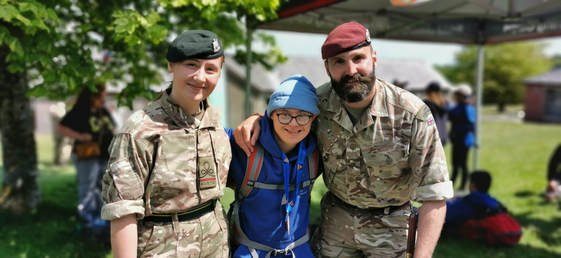 Boy with down syndrome is on the jubilee challenge at dartmoor in between two people wearing military outfits and baret hats