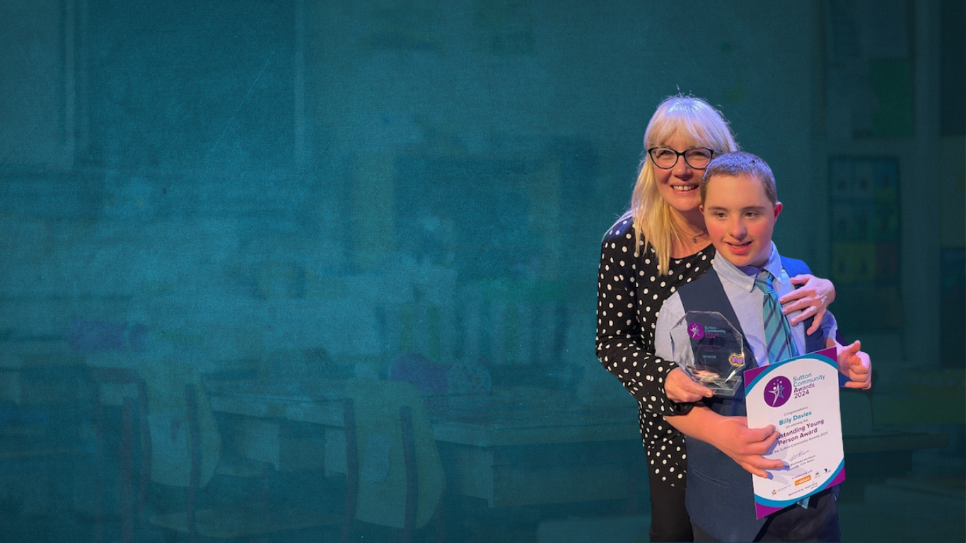 Picture of Lu and Billy, Lu is hugging her son billy from behind whilst holding an award and her son is in front holding a certificate in his hand that says 'Sutton Community Awards'