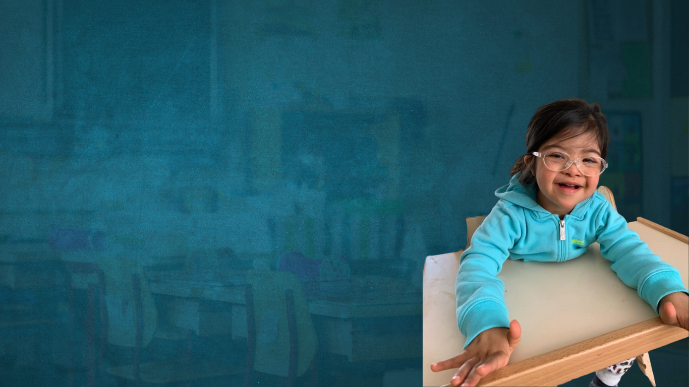 Young child sitting on a table smiling at the camera and wearing glasses