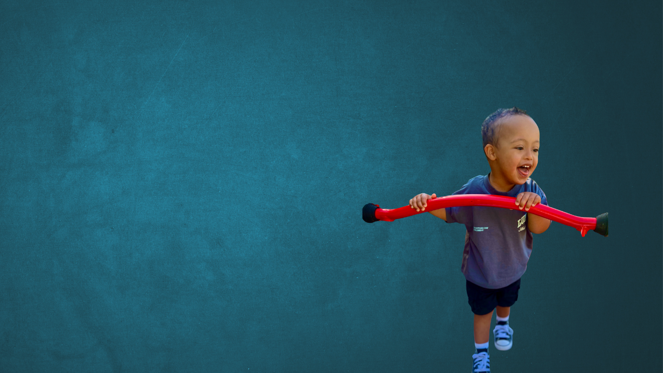Child holding bars at a playground for support and looking off the side smiling