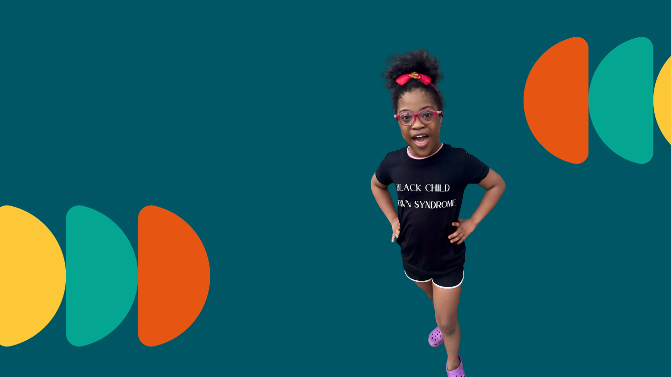 Simone, daughter of Tonye Faloughi-Ekezie from Black Child Down Syndrome is posing wearing a top with the words 'Black Child Down Syndrome' on it